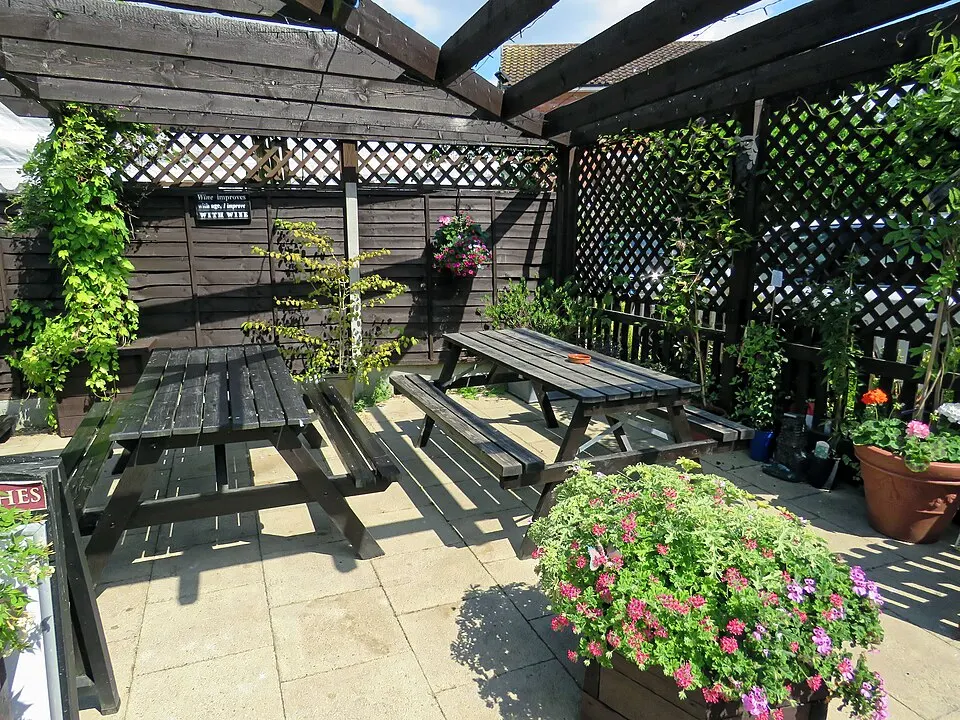 Wood pergola with lattice panels shading picnic tables and planters
